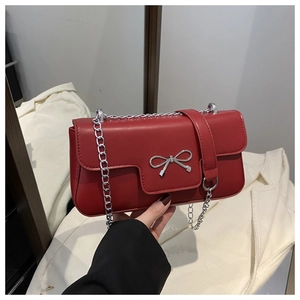 Detail of red PU leather bag featuring a silver metal bow buckle and elegant chain strap
