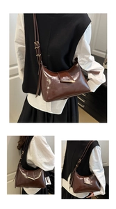 Close-up of dark brown glossy patent leather shoulder bag with golden metal hardware detail