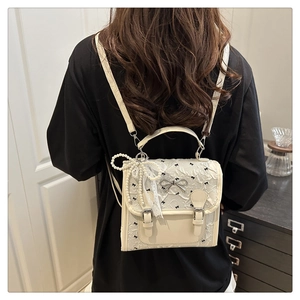 Detail of white lace texture backpack with a silver bow clasp and pearl charm