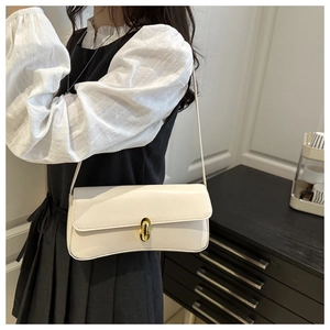 Detailed close-up of the vintage lock buckle on a beige leather underarm bag