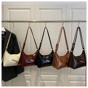 Row of minimalist PU leather underarm bags in five colors hanging on a metal rack