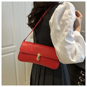 Detail of red matte leather underarm bag with gold oval twist lock and slim shoulder strap