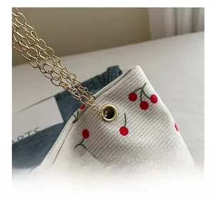 Macro shot of corduroy fabric with cherry print and golden metal grommet details