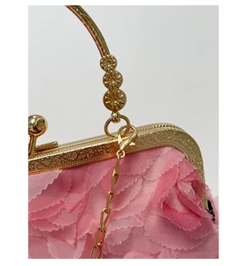 Close-up of pink flower petals and gold metal frame with intricate heart engravings