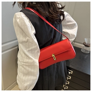 Close-up of a vintage red leather baguette bag featuring an oval gold metallic clasp