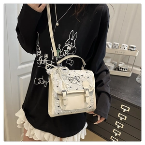 Detail of white lace handbag with pearl chain and bow decoration in home setting