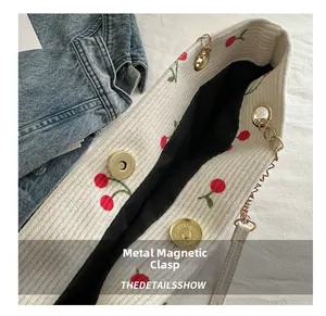 Detail of gold magnetic clasp and cherry print on ivory canvas tote bag strap