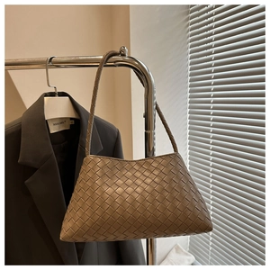 Close-up of woven texture and trapezoid silhouette of the brown leather shoulder bag
