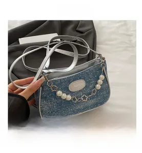 Detailaufnahme der blauen Denim-Umhängetasche mit Perlenkette und Silberriemen