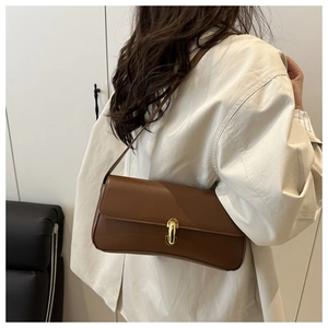 Detail of a brown French vintage underarm bag with gold metal clasp on a model shoulder