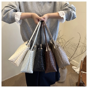 Detail showing hand-held woven leather handbags in white, blue, black, brown, and grey