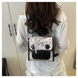 Detail of pink floral jacquard backpack with black bows and pearl lace charm