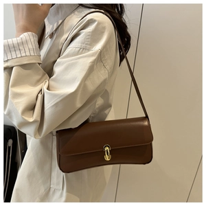 Detail of a dark brown baguette bag featuring a sophisticated gold U-shaped metal buckle