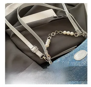 Detail der hellblauen Jeans-Tasche mit Glitzer, Silber-Plakette und schöner Perlenkette