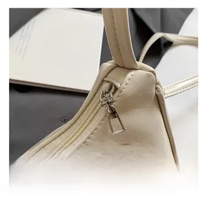 Macro detail of high-quality metal zipper and textured beige leather on underarm bag