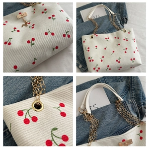 Detail of cherry print corduroy tote bag featuring golden deer charm and twist lock