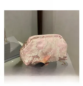 Detail of pink satin bag featuring exquisite white lace floral embroidery and gold chain