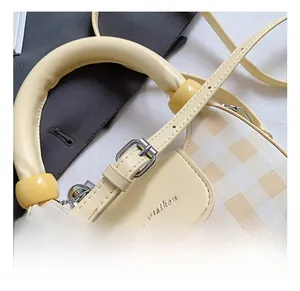 Detail of adjustable shoulder strap with silver buckle on plaid small crossbody bag