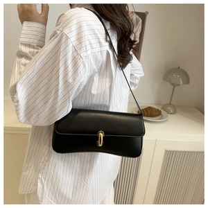 Detailed view of a black minimalist underarm bag with an elegant golden oval metal buckle