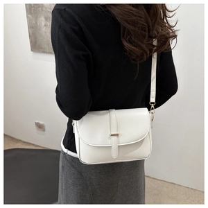Dettaglio di una borsa a tracolla bianca minimalista con fibbia dorata su una modella