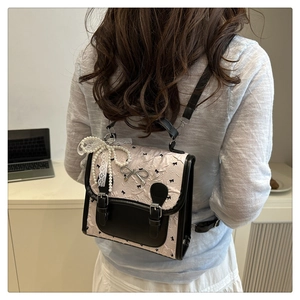 Rear view of a mini pink backpack with black bow patterns and lace pearl pendant detail