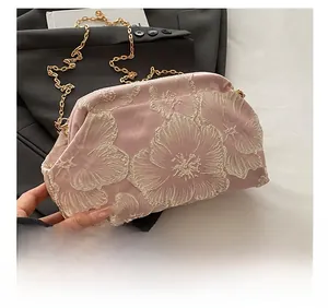 Close-up of pink satin clutch bag with floral embroidery and golden metal chain