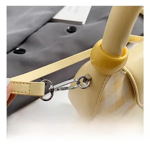 Detail shot of silver lobster clasp and yellow plaid fabric on a stylish crossbody bag
