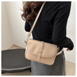 Dettaglio borsa a sella beige con cinturino decorativo e fibbia in metallo dorato