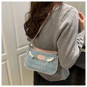 Detailansicht der hellblauen Jeans-Umhängetasche mit rosa Paspelierung und Perlenkette