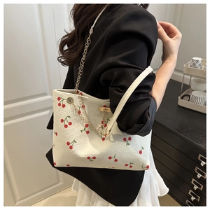 Detail of off-white corduroy tote bag with cherry print and golden chain strap