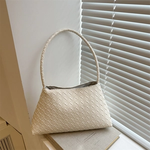 Minimalist white woven faux leather hobo bag with top handle on books background