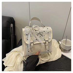 Detail of vintage beige handbag with lace embroidery and pearl bow accessory