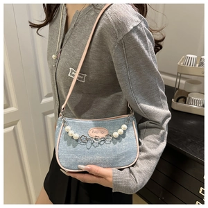Detail der Jeans-Schultertasche mit rosa Lederbesatz und Perlen-Blumen-Deko-Kette