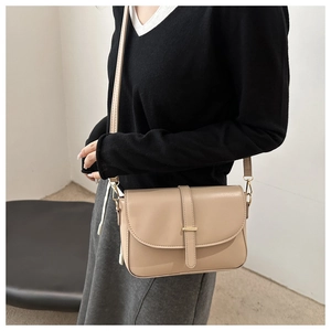 Dettaglio della borsa a sella beige in pelle con fibbia dorata e tracolla sottile