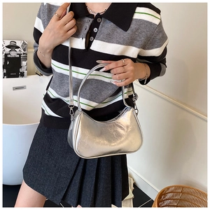 Silver metallic dumpling bag shown with a slim shoulder strap and stylish casual outfit