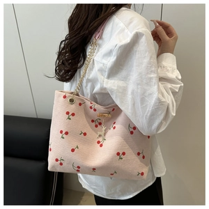 Pink corduroy tote bag detail with cherry print, golden chain, and deer charm