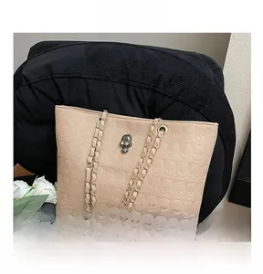 Close-up of beige tote bag featuring skull embossed pattern and metallic skull clasp