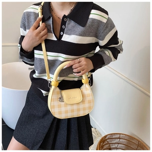 Detail of yellow checkered crescent bag with H-letter logo and golden heart charm
