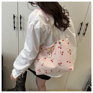 Detail view of pink corduroy tote bag featuring red cherry print and deer charm