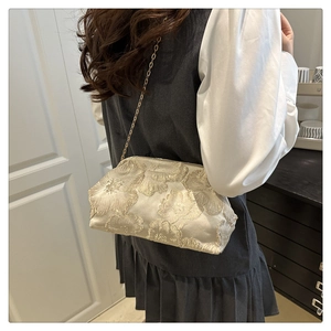 Detail of floral embroidery on beige satin shell bag with gold chain strap