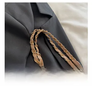 Detail of khaki leather interwoven with gold metal chain strap on a black tote bag