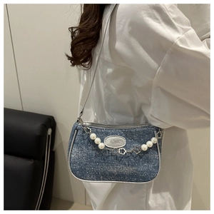 Detail der gewaschenen Denim-Achseltasche mit Perlenblumenkette an einem Modell
