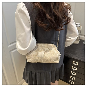 Detail of champagne shell bag featuring luxury 3D floral embroidery and gold chain strap