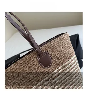Détail du sac à main en paille tressée avec motif à rayures et coutures en cuir fin