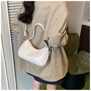 Close-up of cream crescent shoulder bag with glossy leather finish and silver hardware