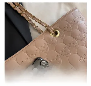 Close-up of embossed skull pattern on leather tote bag with rhinestone-eyed metal skull hardware