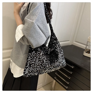 Detailed view of shimmering black sequins on a large tote bag with reflective metallic shine
