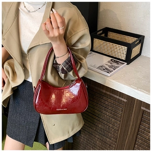 Close-up of wine red patent leather shoulder bag with chic crinkled texture detail
