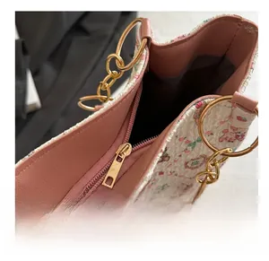 Gros plan sur la fermeture éclair dorée et la doublure rose du sac à main à fleurs
