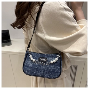 Detail der Jeans-Baguette-Tasche mit Perlenkette und Fashion-Label an einem Model